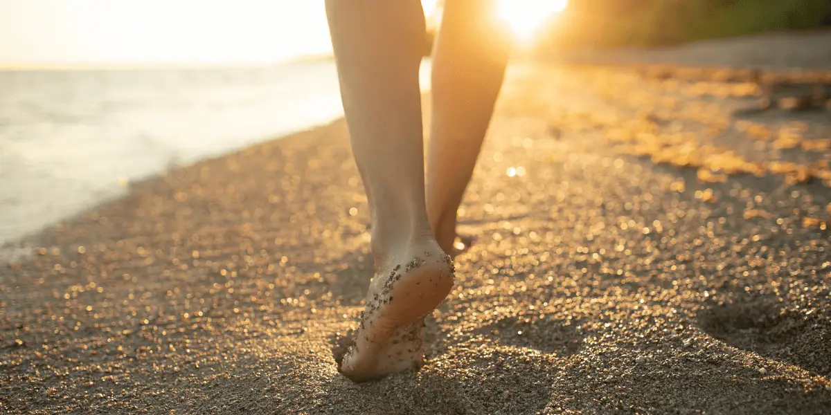 Sunset beach stroll, person practicing grounding exercise by walking