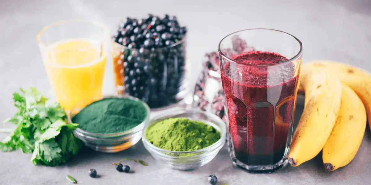 A glass of green smoothie filled with blueberries, bananas, and various fruits - a refreshing heavy metal detox smoothie.