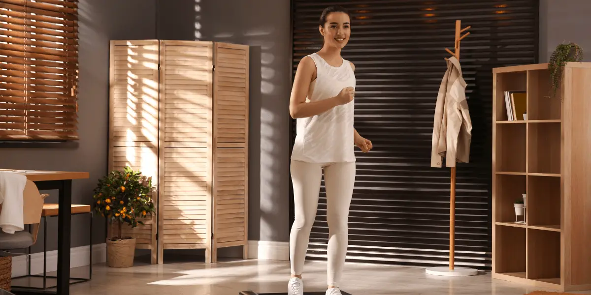 A woman walking on a treadmill in a room during an indoor walking challenge.