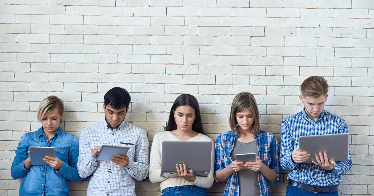 A diverse group of young people sitting together, engrossed in using tablet computers.