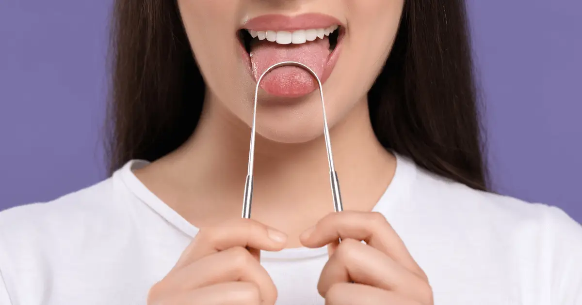 Woman holding tongue scraper, image for tongue scraping.