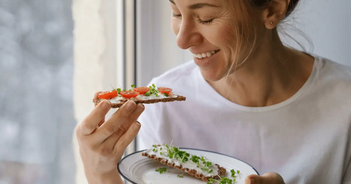 A woman holding a plate of food, practicing intuitive eating.