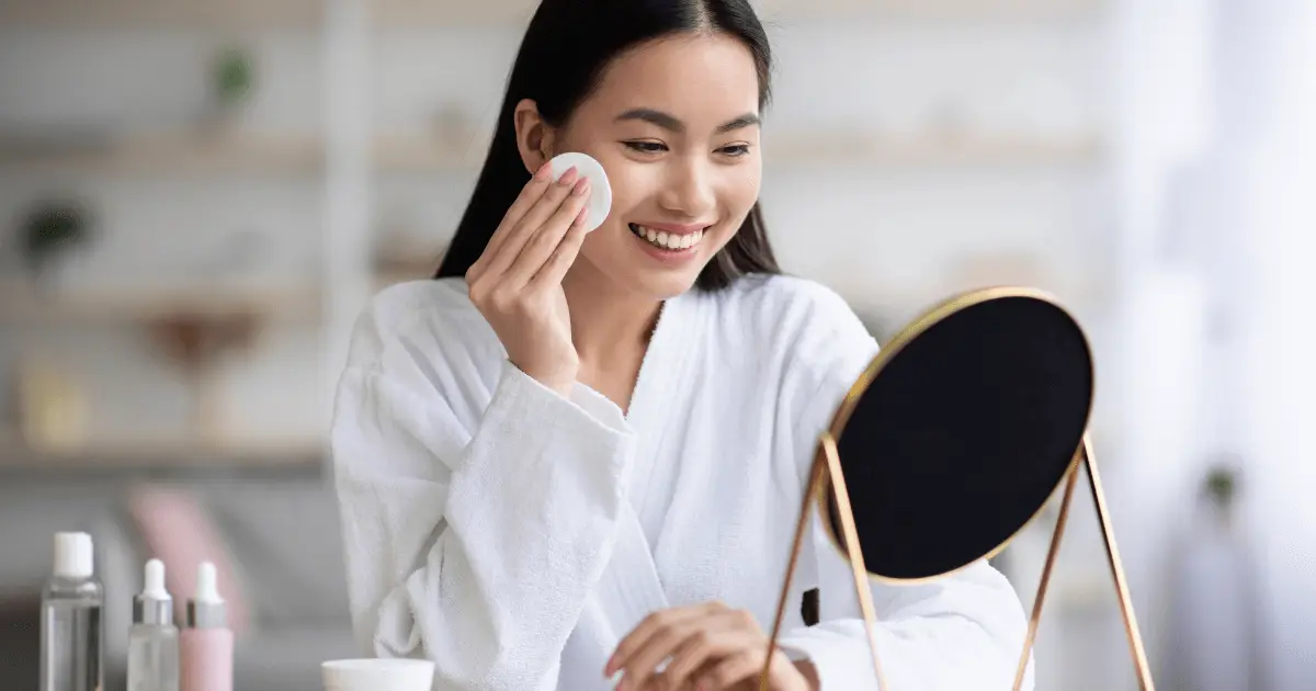 Woman smiling while using glycolic acid facial cleansing pad.