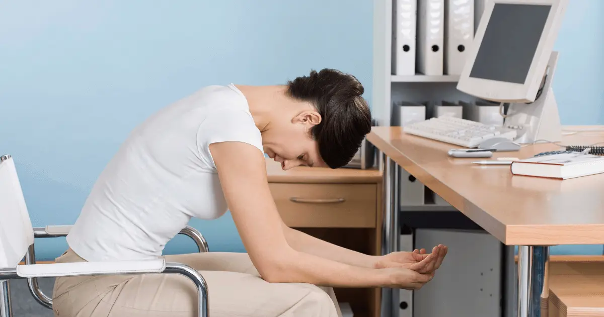 A woman practicing desk yoga, sitting with hands on knees.