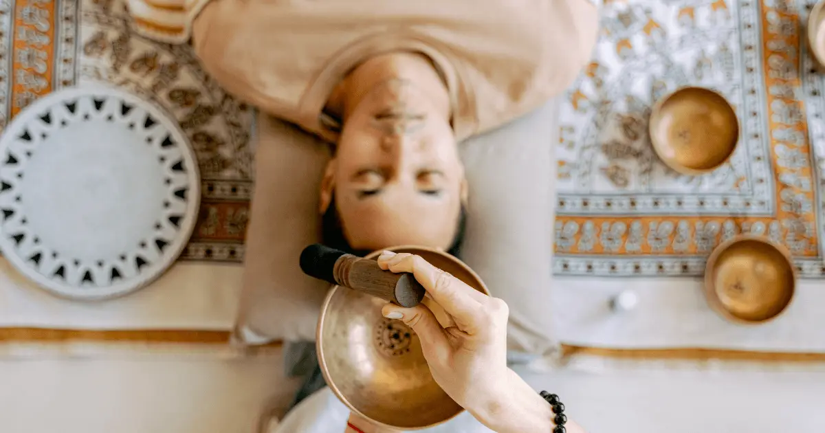 A person lying on a bed, enjoying a bowl of food while immersed in a sound bath meditation experience.