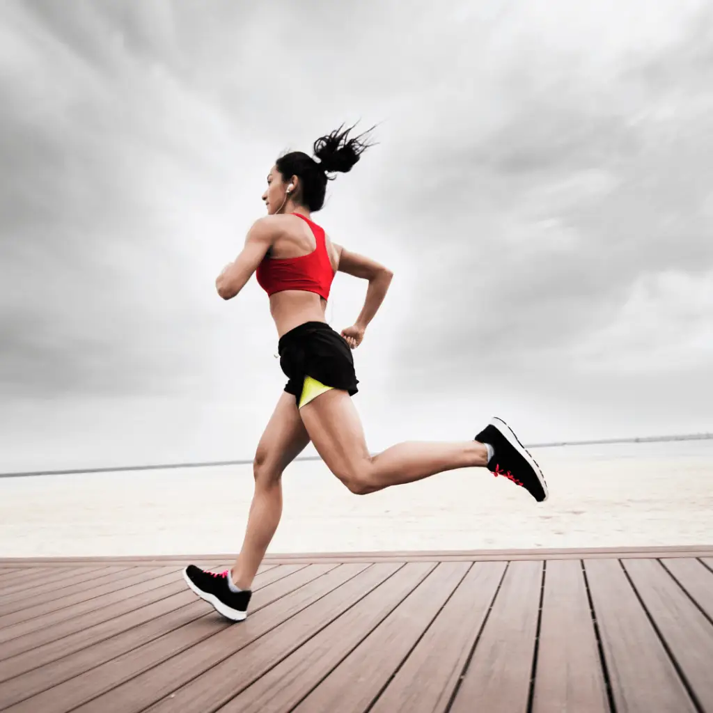 A vibrant athlete energizes herself by running on a wooden boardwalk during a grounding exercise