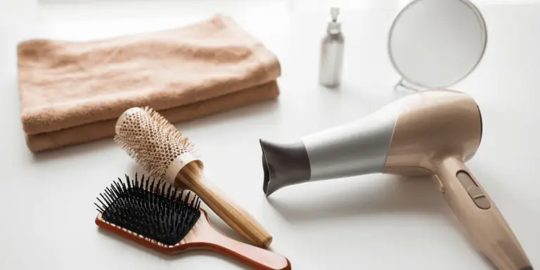Hair care essentials hair dryer, brush, and towel on a white table. Perfect tools for your hair necessities.
