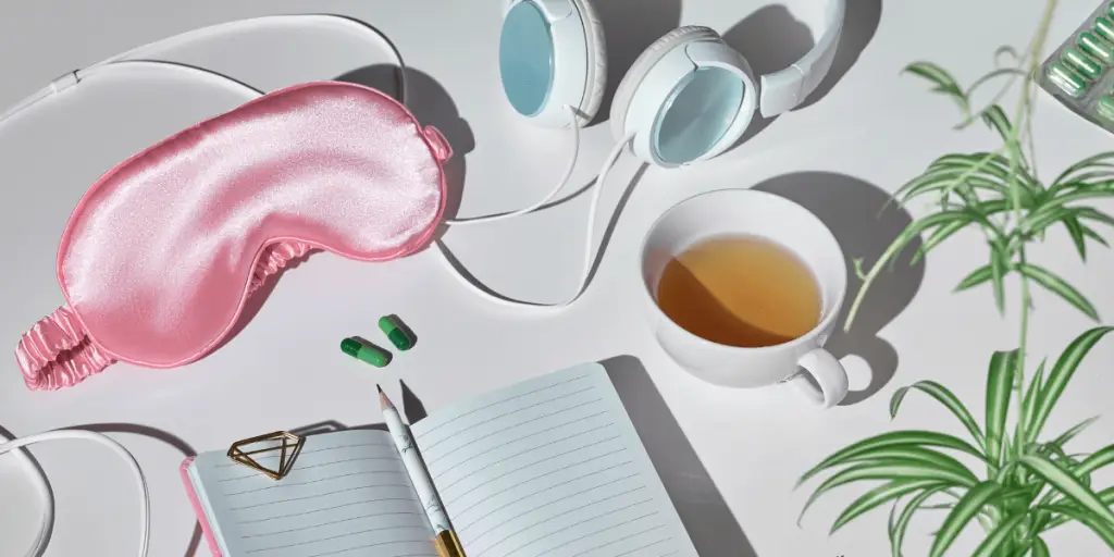 Sleep hygiene essentials eye mask, earphones, and a cup of tea.