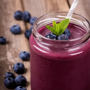 Blueberry smoothie in glass jar on wooden table, heavy metal detox smoothie