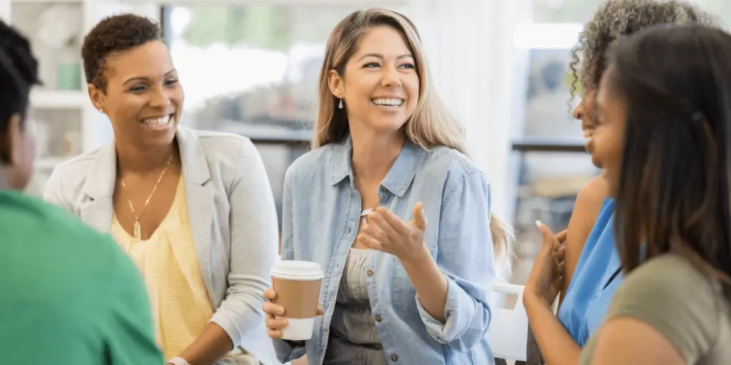 A circle of women talking and laughing, exemplifying a supportive community and the importance of protecting energy.