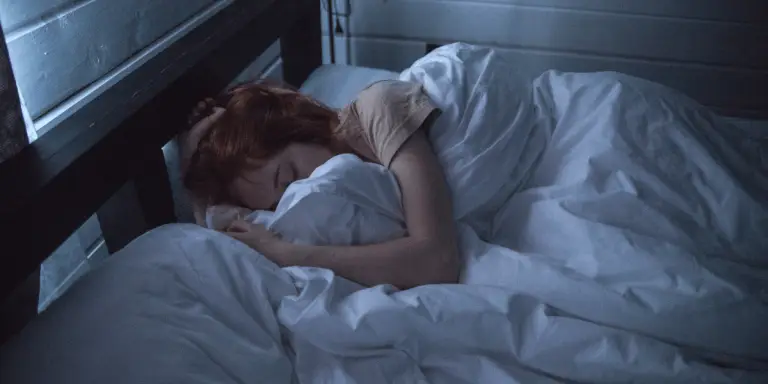An illustration of a woman peacefully resting in bed with white sheets, in slow wave sleep.