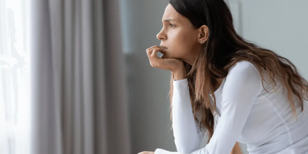 Sitting woman looks out window. Grounding activity to manage anxiety.