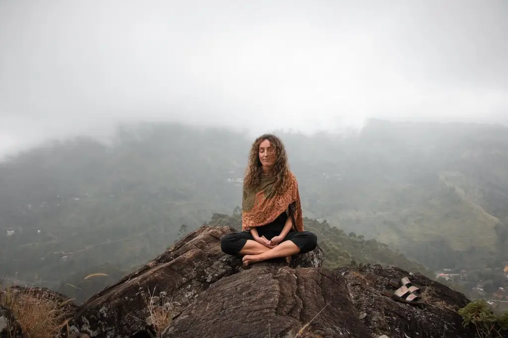 Traditional grounding exercise_ woman sitting in yoga pose on mountain