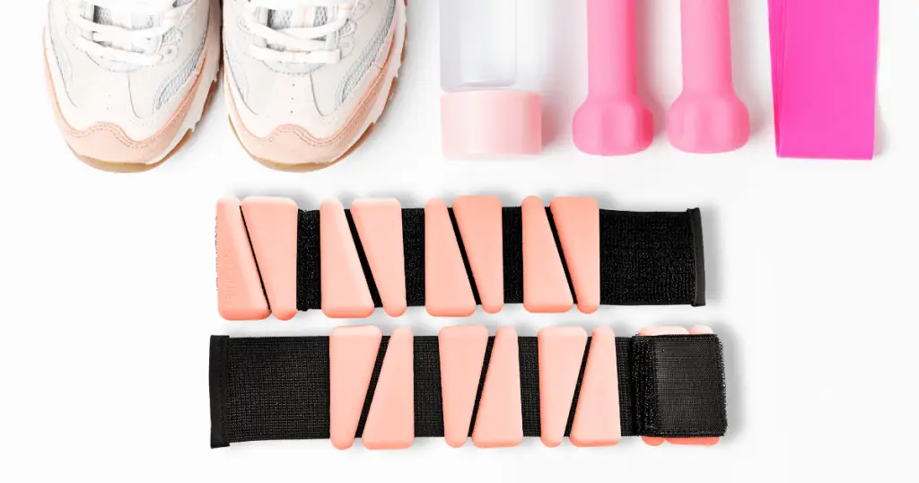 A pair of sneakers and pink rubber bands, along with ankle weights, neatly arranged.