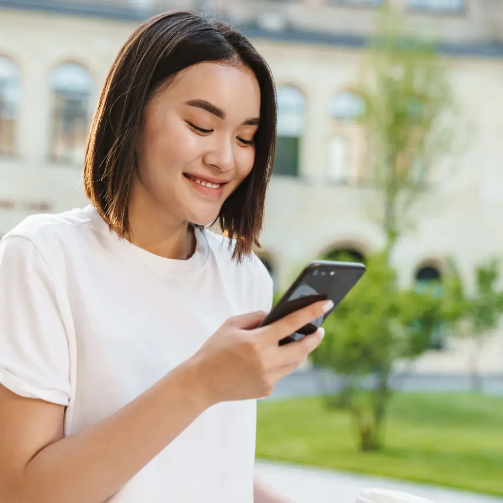 An Asian woman enjoying outdoor activities while using her smartphone, possibly playing Games for Health.