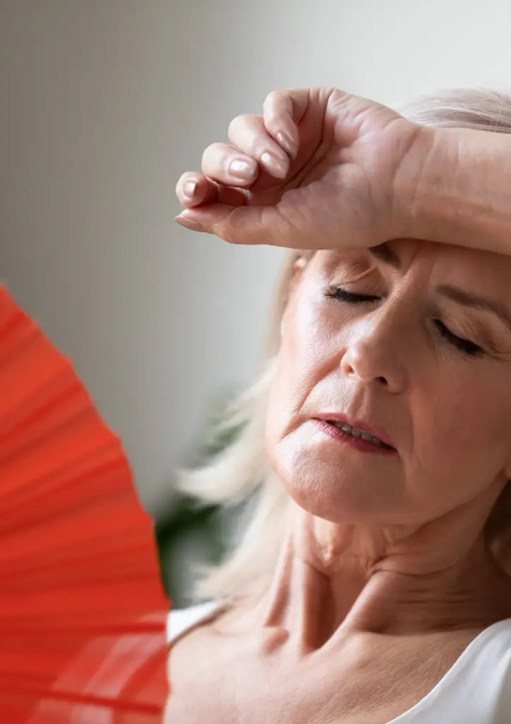 Woman holding red fan, symbolizing relief during menopause.