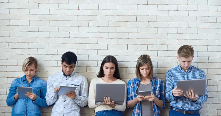 A diverse group of young people sitting together, engrossed in using tablet computers.