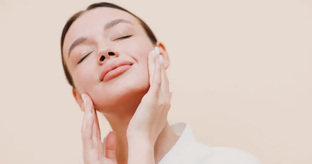 A woman practicing facial yoga, gently touching her face with her hands to enhance relaxation and rejuvenation.