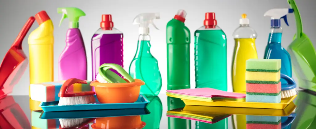 A variety of cleaning products neatly arranged on a table, showcasing bottles, sprays, and sponges in vibrant colors.