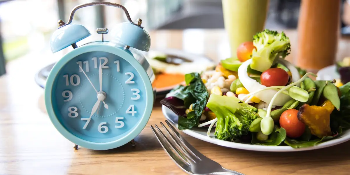 A clock and a diverse array of whole foods filling a plate, showcasing a balanced and nutritious approach to intermittent fasting for sustainable weight loss benefits.