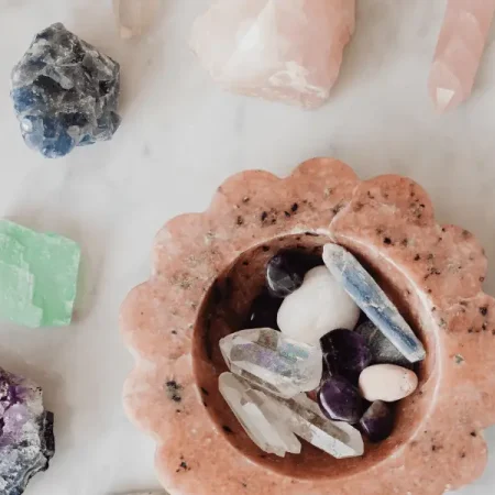A collection of crystals and stones arranged in a bowl on a marble counter, promoting energy protection.
