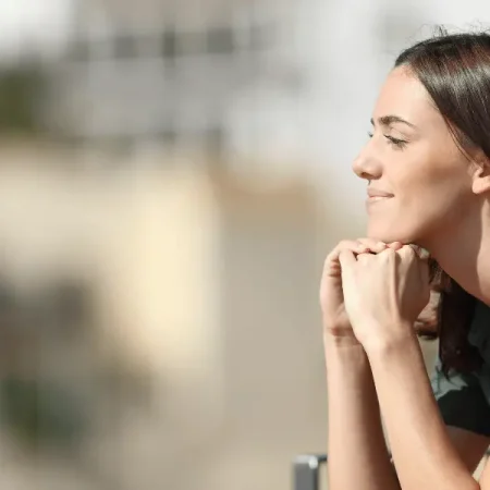 A lady seated on a bench, staring upwards. Engaged in shadow work, feeling fulfilled.